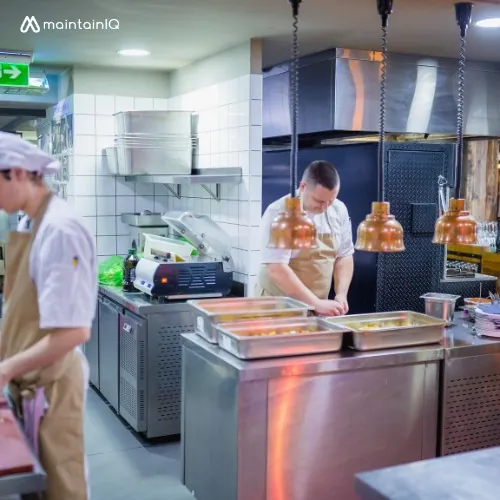 Cooks preparing hotel pans of food at a stainless steel line in a commercial kitchen before service
